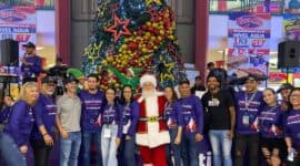 Santa Claus rodeado de empleados y aliados de Metropolis Valencia con el árbol de navidad al fondo durante el inicio de la navidad mágica