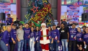 Santa Claus rodeado de empleados y aliados de Metropolis Valencia con el árbol de navidad al fondo durante el inicio de la navidad mágica