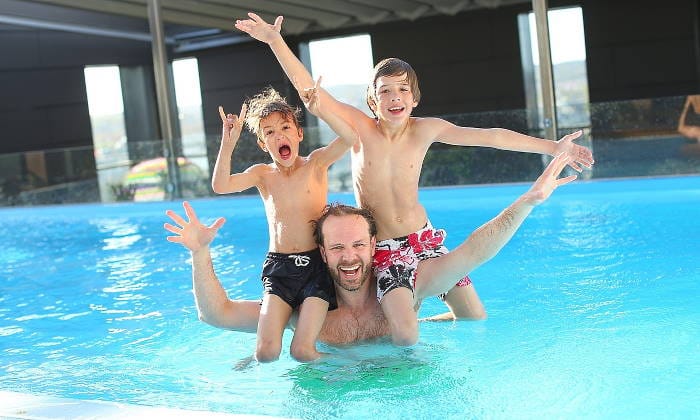 Niños en los hombros de su padre en una piscina celebran a papá en su día
